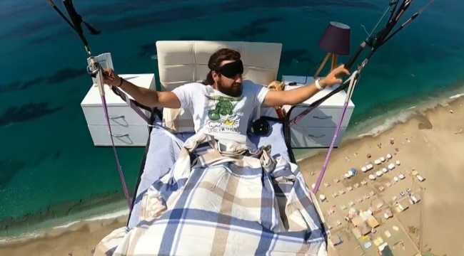 Yamaç paraşütüne bağlanan yatağa gökyüzünde uzandı